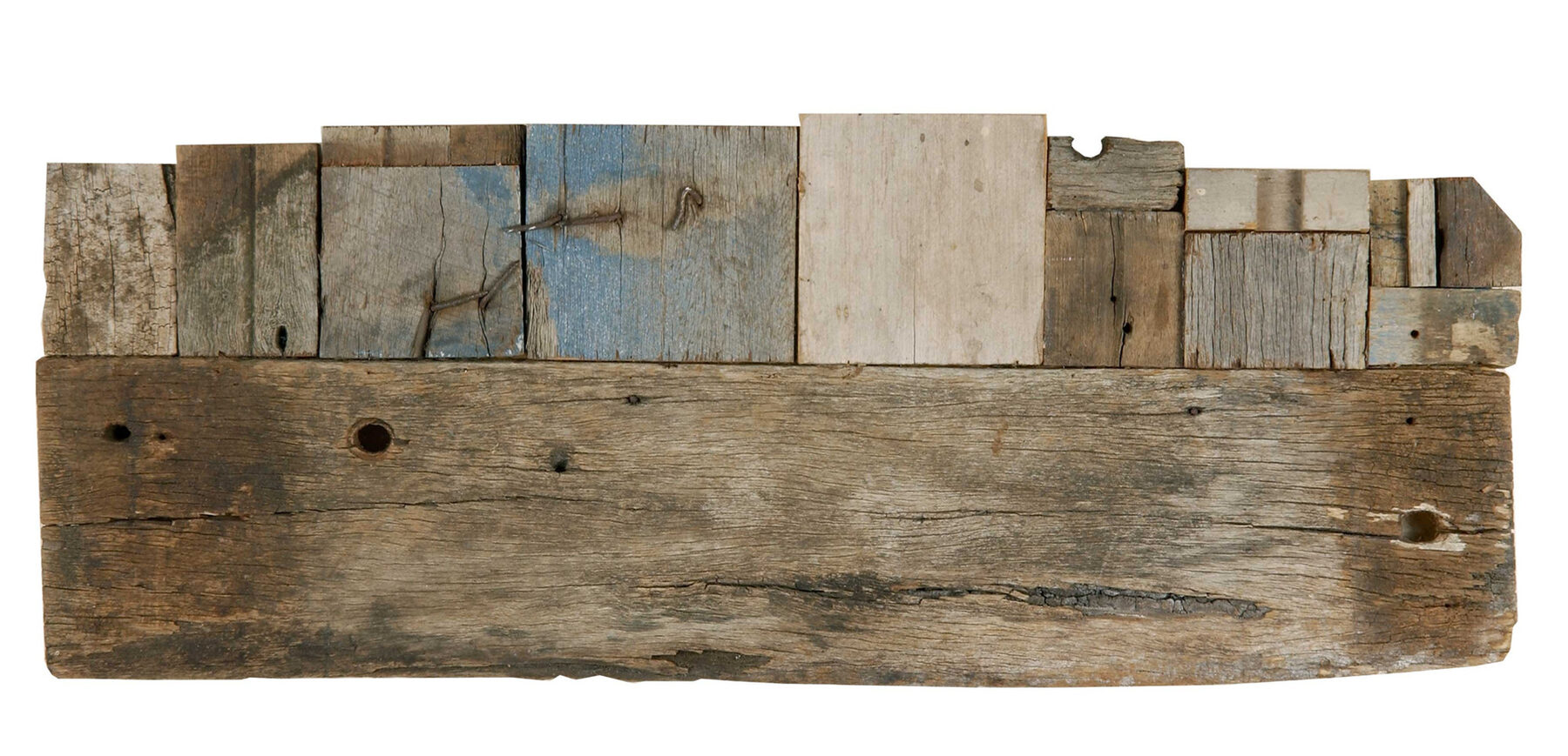 Small offcuts of pale and blue-painted weathered timber stacked into a low horizontal skyline along a long split board.