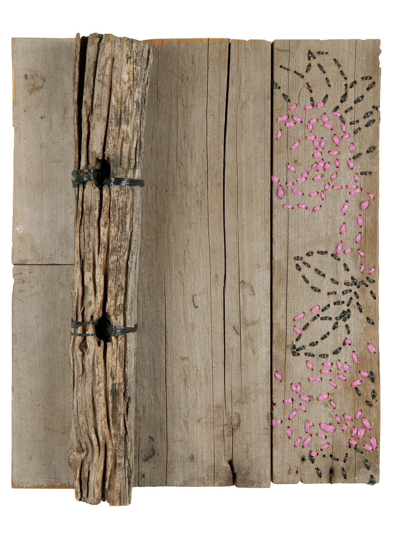 Weathered timber strips side by side, one bound down its edge with black baling twine like a book spine, beside a blue-grey painted board.
